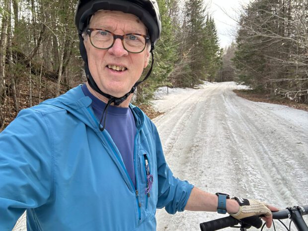 man wearing blue on a bike looking into the camera on an icy trail