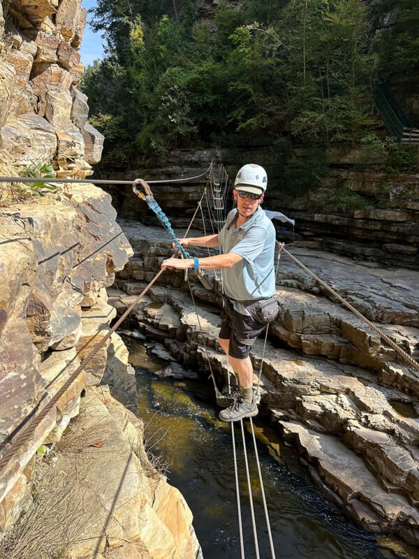 Guide Chuck Fries crosses the Ausable River on a cable bridge that’s part of the via ferrata route.