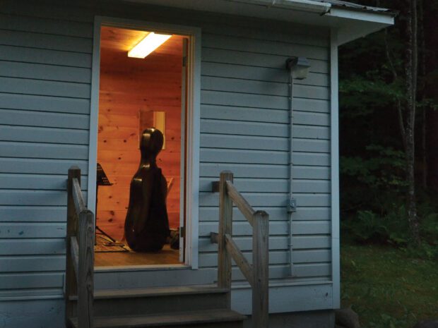 A string instrument sitting inside the open door of a cabin
