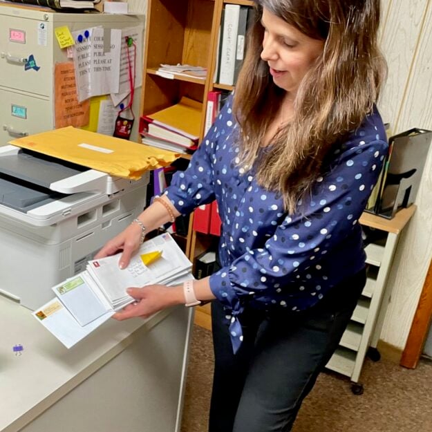 Lake Pleasant Town Clerk Stephanie Smith with a stack of tax returns that arrived all at once at the local post office up to months after they had been mailed.