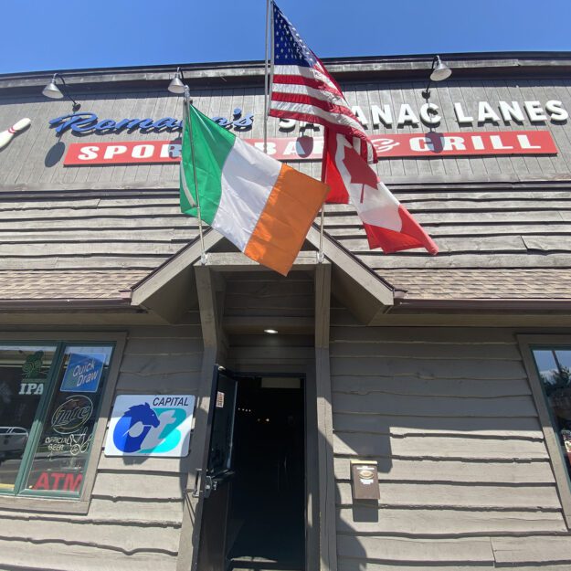 a trio of flags in front of a business: Italian, American and Canadian