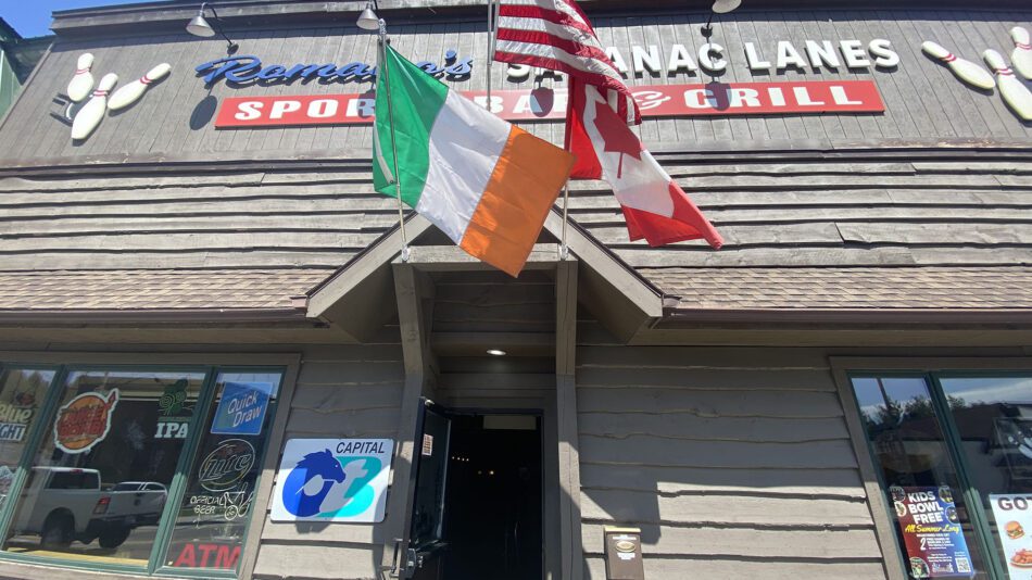 a trio of flags in front of a business: Italian, American and Canadian