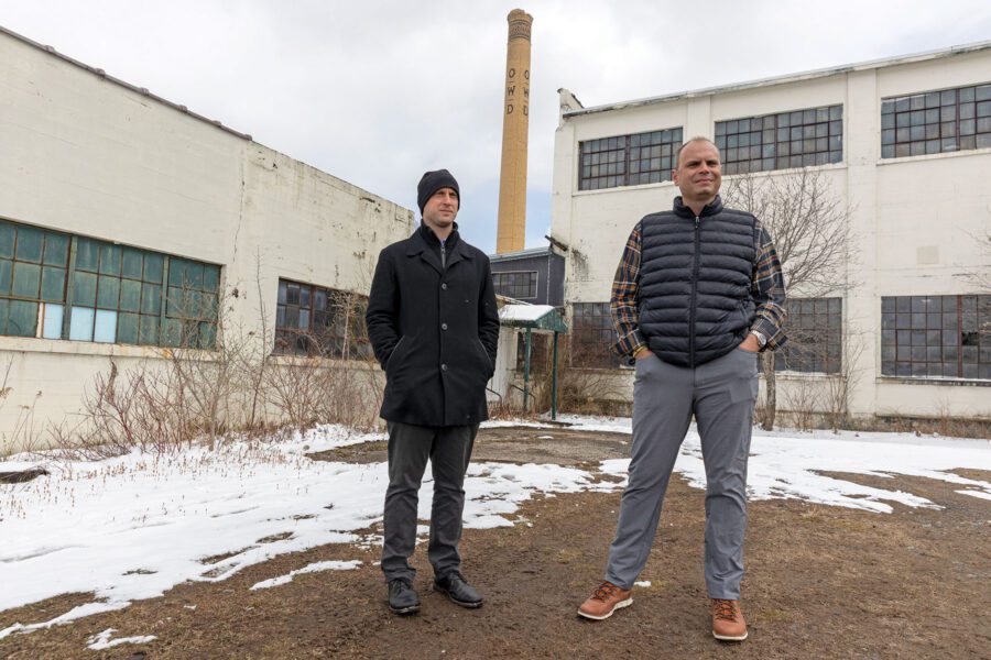 Two men stand outside an old factory