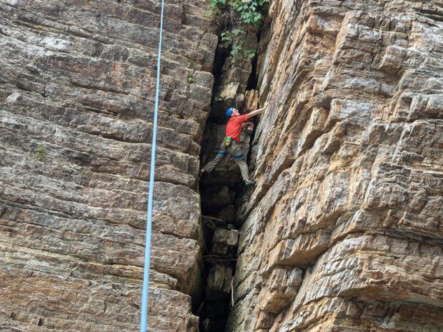 man climbing in narrow rock wall