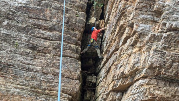 man climbing in narrow rock wall