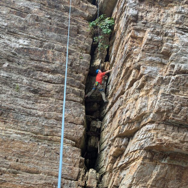 man climbing in narrow rock wall