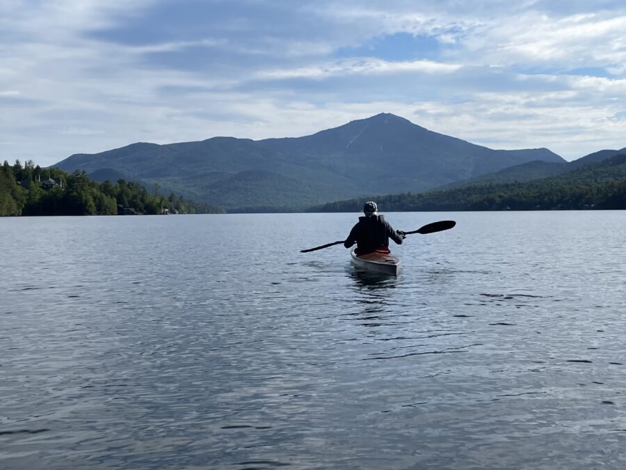 man paddling on a lake with a mountain in the background
