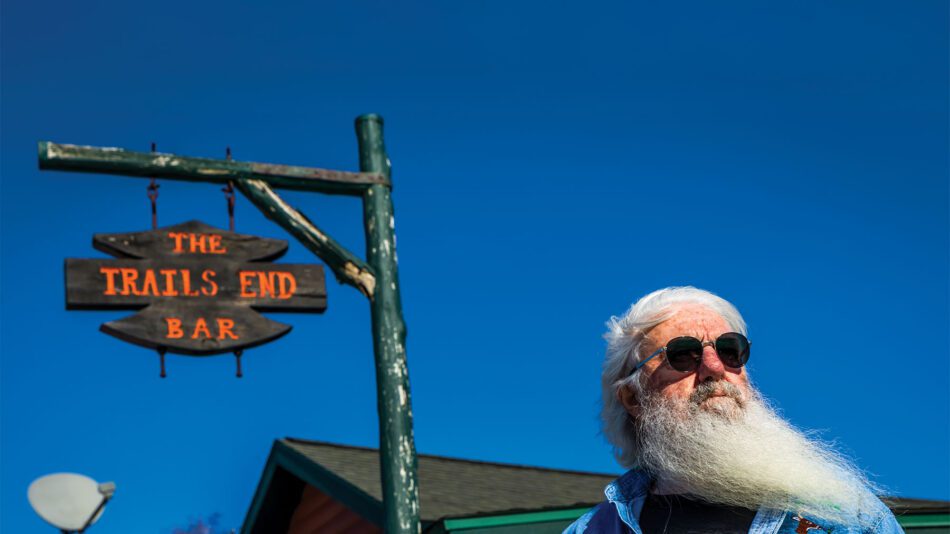 Man with white beard and sunglasses in front of the Trails End Bar