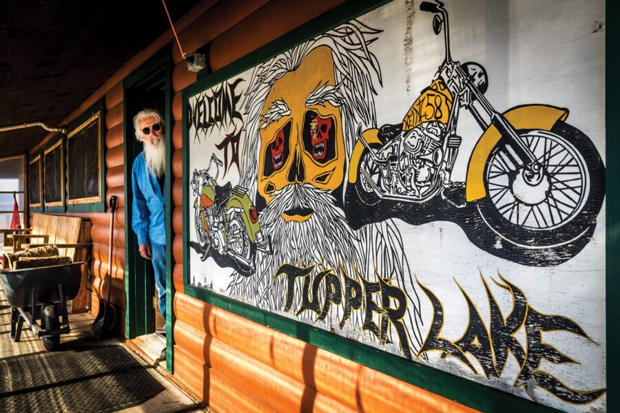 Man with white beard and sunglasses in the doorway of the Trails End Bar in Tupper Lake