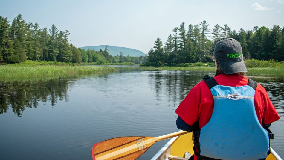 woman in canoe seen from behind with paddle in hand
