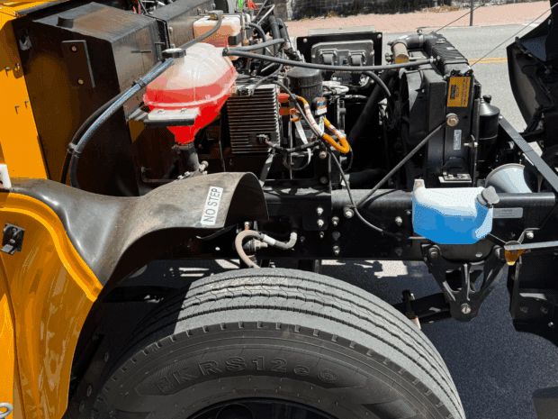 A yellow school bus engine compartment displays the mechanical systems
