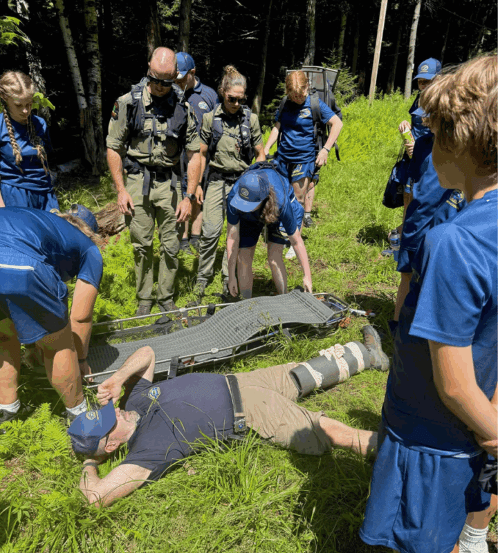 Man lays on the ground with youth observing leg splint on green grass