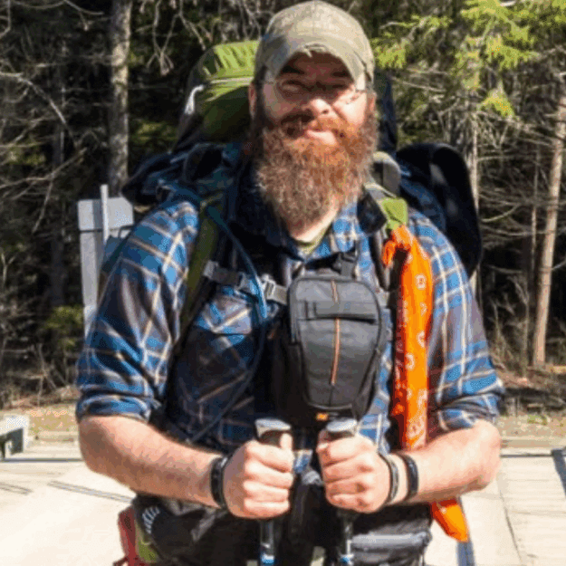 Man on bridge with hiking poles and baseball cap