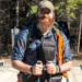 Man on bridge with hiking poles and baseball cap
