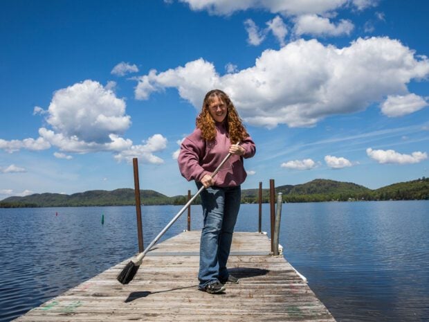 woman with broom on a dock on a sunny day