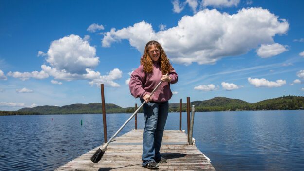 woman with broom on a dock on a sunny day