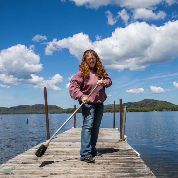 woman with broom on a dock on a sunny day