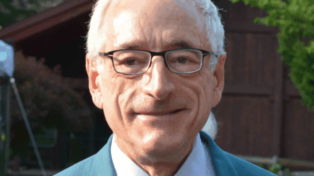 Head shot of man in glasses, blue blazer, white shirt, and tie