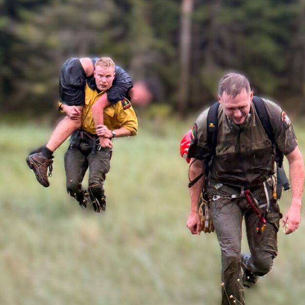 Ranger Lewis carries the patient to the helicopter at Elk Pass.