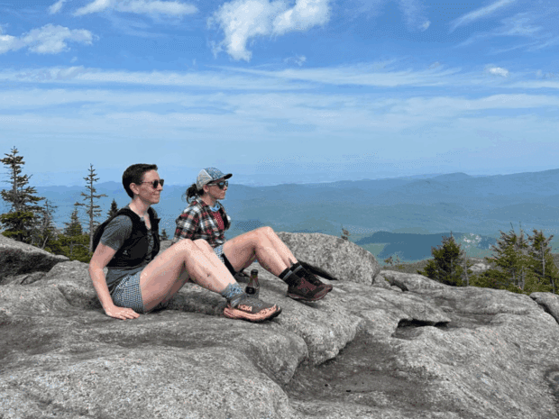 Debbie McElwaine and Katie Rhodes sitting in profile positions on the summit of on Grace Peak. Photo courtesy of Katie Rhodes