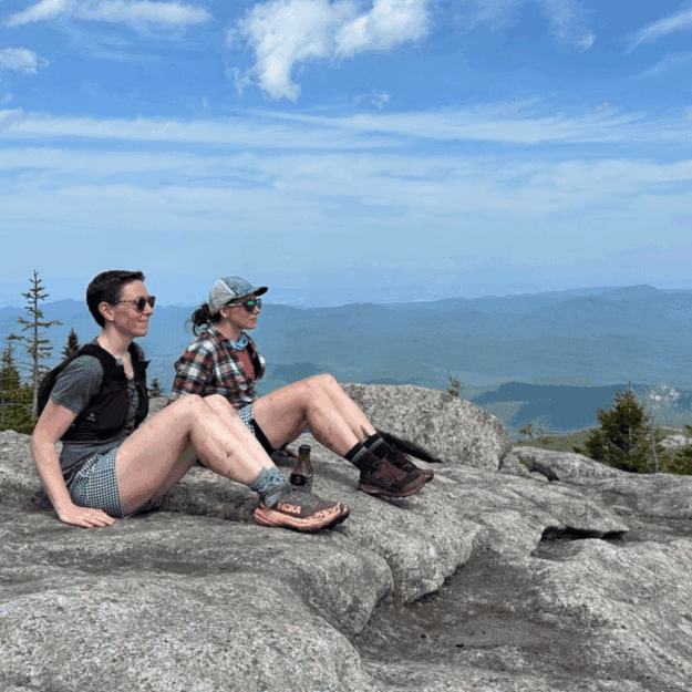 Debbie McElwaine and Katie Rhodes sitting in profile positions on the summit of on Grace Peak. Photo courtesy of Katie Rhodes