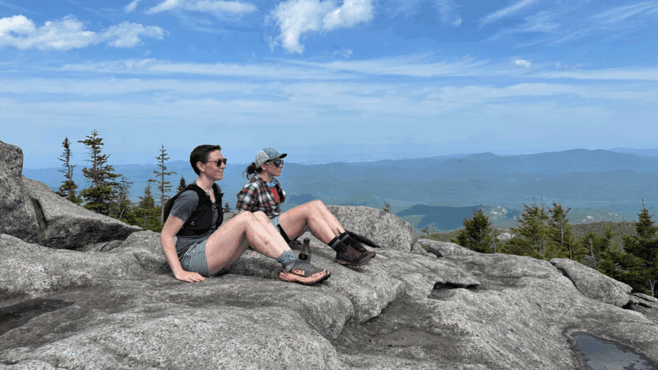 Debbie McElwaine and Katie Rhodes sitting in profile positions on the summit of on Grace Peak. Photo courtesy of Katie Rhodes