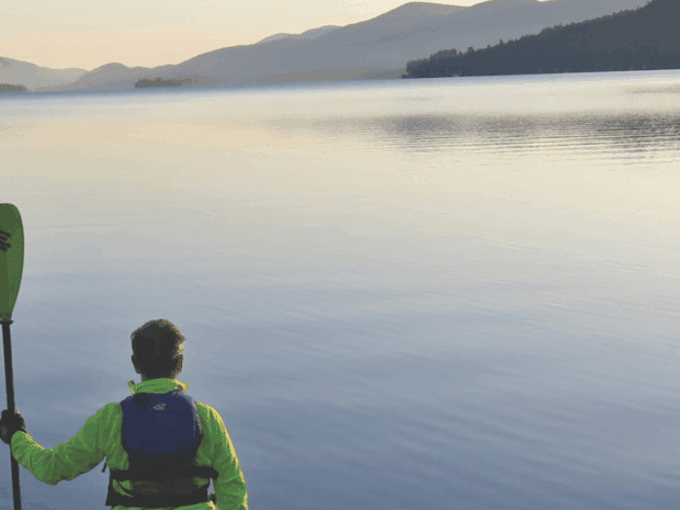 The author faces the lake paddle in hand with one end resting on the sand on the lakeshore at the start of the journey in Lake George village.