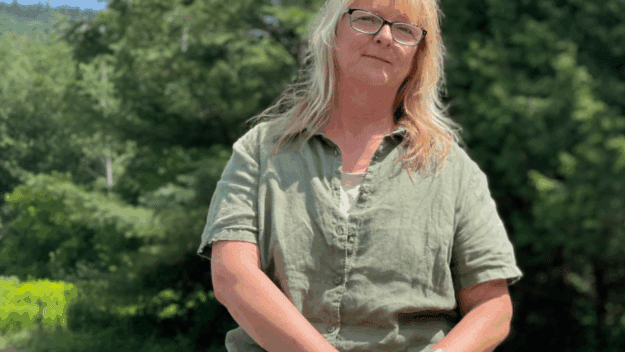 Photo of Sue Hagar by Tim Rowland. Older blonde woman in green shirt and pants.