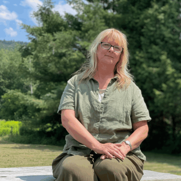 Photo of Sue Hagar by Tim Rowland. Older blonde woman in green shirt and pants.