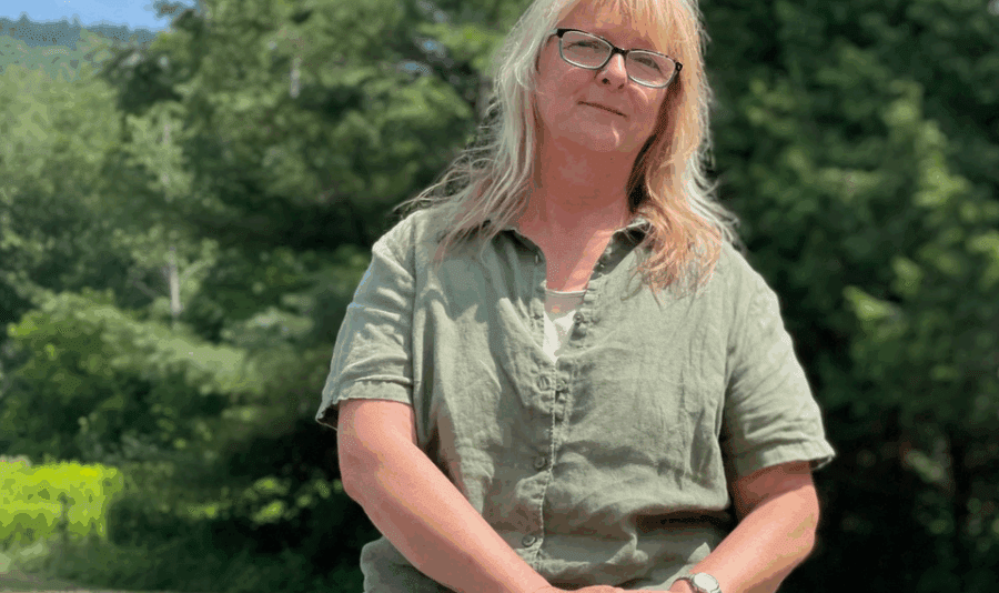 Photo of Sue Hagar by Tim Rowland. Older blonde woman in green shirt and pants.