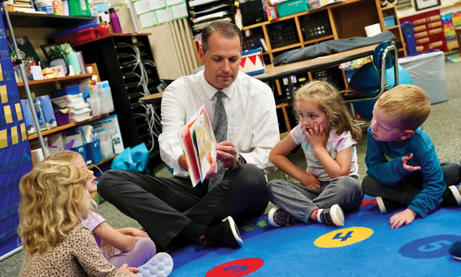 man reading to children on a colorful rug