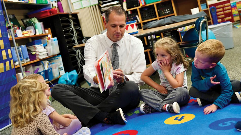 man reading to children on a colorful rug