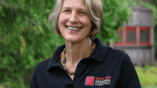 Headshot of woman in black button up shirt with Sagamore logo on it