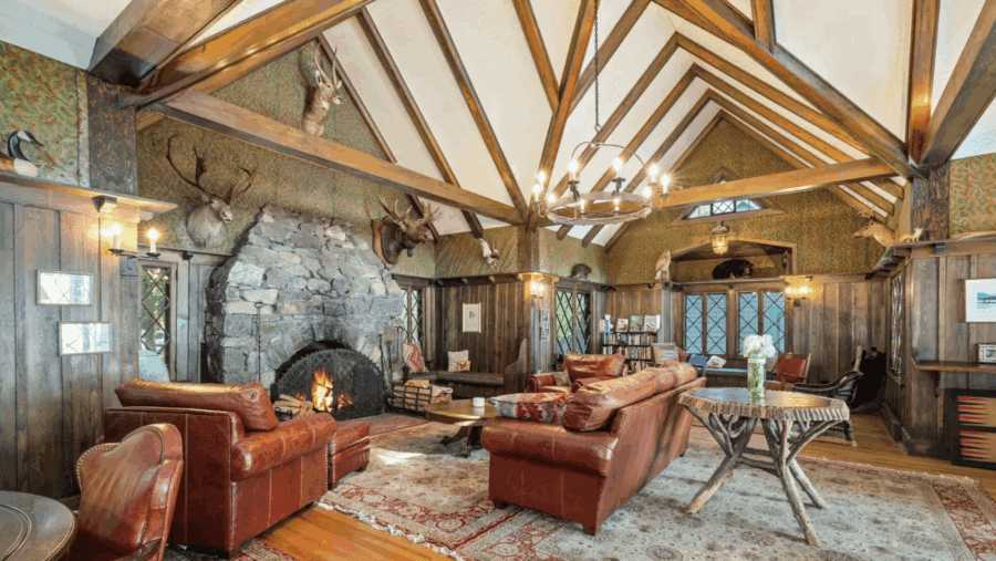 Great room with stone fireplace and vaulted ceiling  Camp Iroquois in Saranac Lake, is a historic 4,000-square-foot Great Camp nestled on 8.6 secluded, wooded acres. Currently listed for $4.25 million, the property is being auctioned on Sept. 23 without reserve.