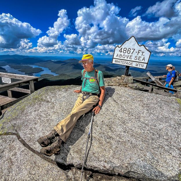 man sitting on a rock at the top of a mountain in the Adirondacks