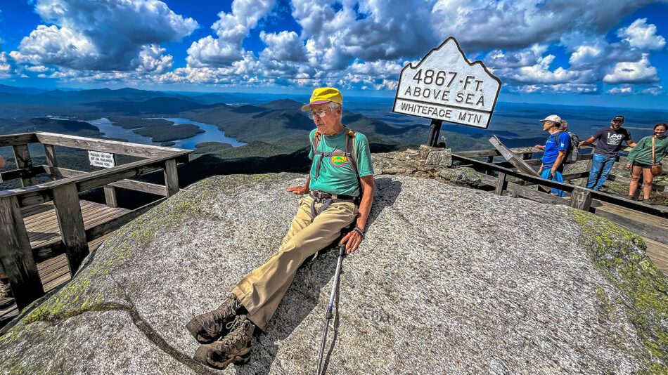 man sitting on a rock at the top of a mountain in the Adirondacks